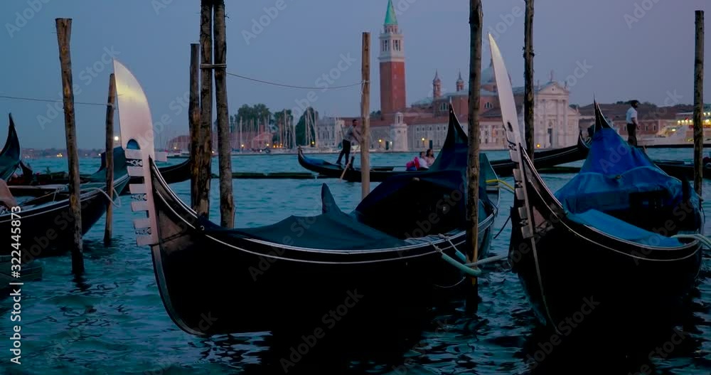 Dusk, blue hour shot of docked traditional, venetian gondolas rocking on the waves Dusk, blue hour shot of docked traditional, venetian gondolas rocking on the waves