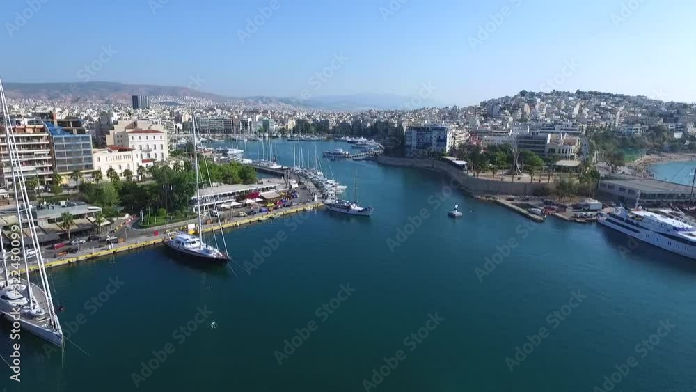 Aerial fly shot with drone over the sea close to the port with view the town, boats and sailboats with a sunny day and blue sky. Aerial fly shot with drone over the sea close to the port with view the town, boats and sailboats with a sunny day and blue sky.