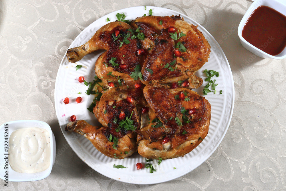 Pan fried crispy chicken tabaka served on a white plate, shallow focus Pan fried crispy chicken tabaka served on a white plate, shallow focus
