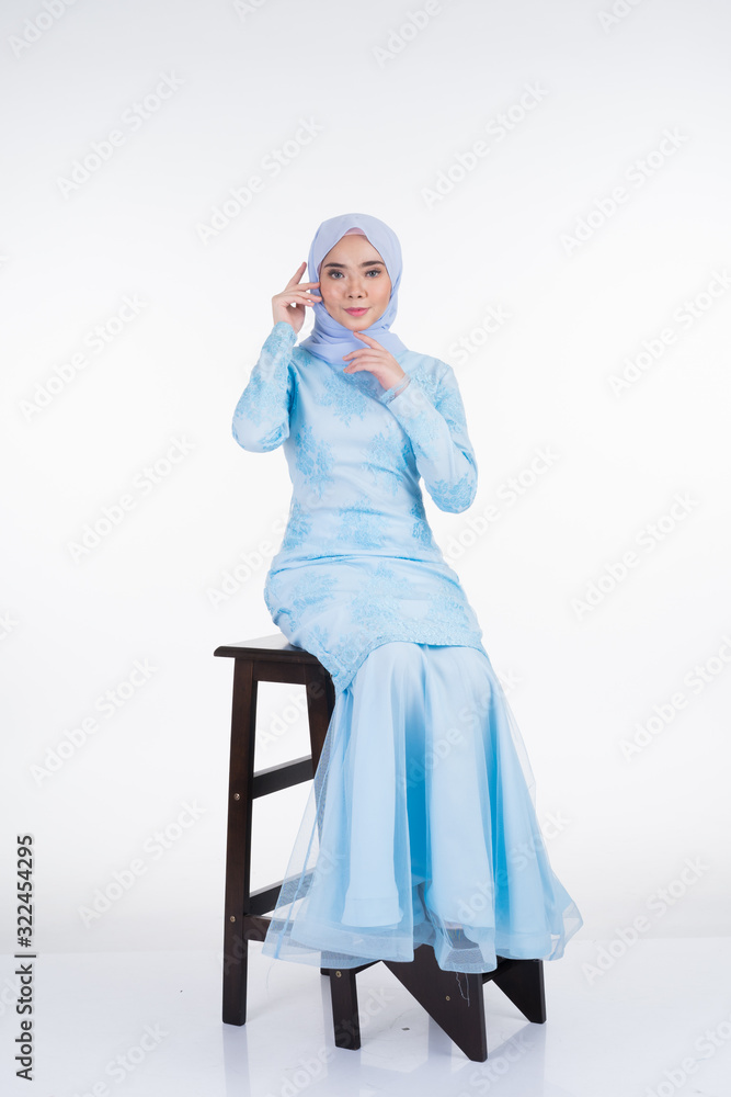 Attractive Muslim female model wearing pastel blue modern kurung with hijab, a urban lifestyle apparel for Muslim women isolated on white background. Beauty and hijab fashion concept. Full length