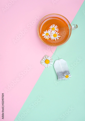 tea bag, daisy flower and chamomile tea in cup. antidepression organic healthy beverage. creative minimal concept. copy space.  photo