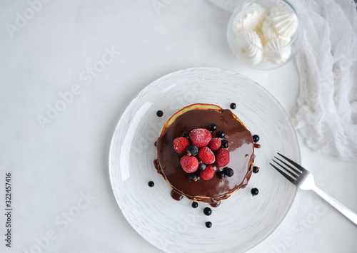 Homemade pancakes with chocolate and fresh berries on a white background. Image with copy space, top view. photo