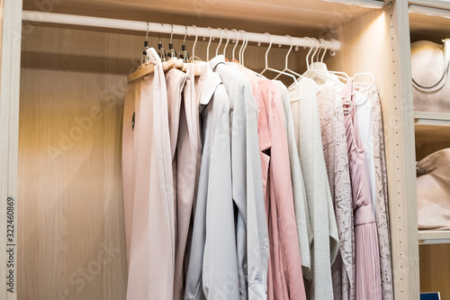 row of shirts hang in wardrobe at home.clothes hanging on rail. modern dressing room interior detail.modern closet .wardrobe in home.closet with row of shirts hanging on hanger in wooden wardrobe.