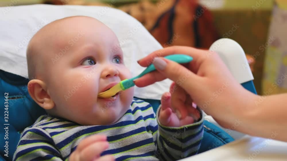 Mother feeding little baby with vegetable mash at home kitchen. Mother feeding little baby with vegetable mash at home kitchen.