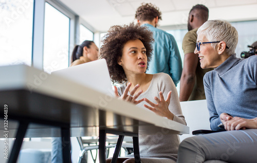Two talented women discussing ideas for the new project at their workplace. They are enjoying the process.