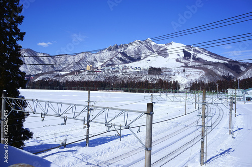 遠くに上越線の列車が見える冬の田園風景