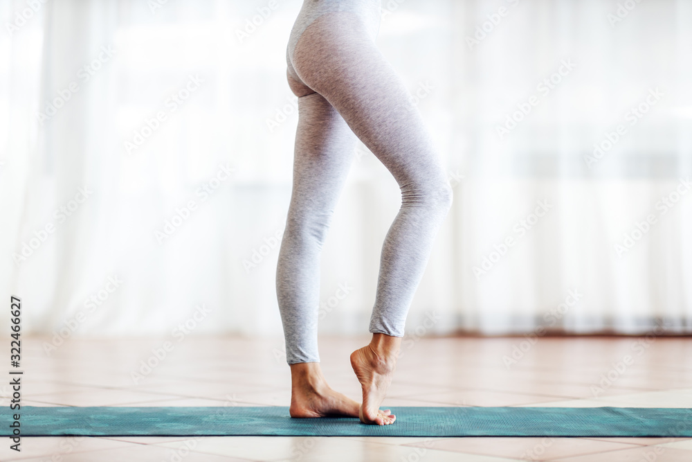 Fototapeta premium Close up of fit slim yogi girl standing on the mat barefoot.
