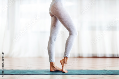 Fototapeta Naklejka Na Ścianę i Meble -  Close up of fit slim yogi girl standing on the mat barefoot.