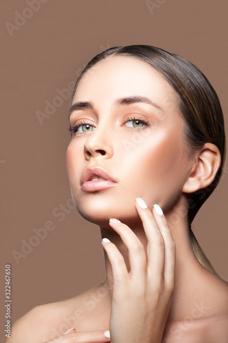 Beauty portrait of young model woman with perfect skin, beige background. 