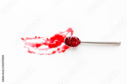 Fruit jam. Red dessert smashed by spoon on white desk