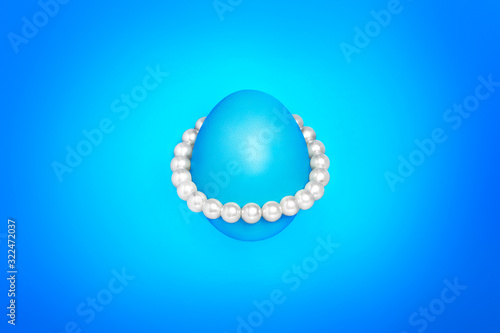 Blue easter egg planet with pearl on a blue background. Luxury concept. Greeting card