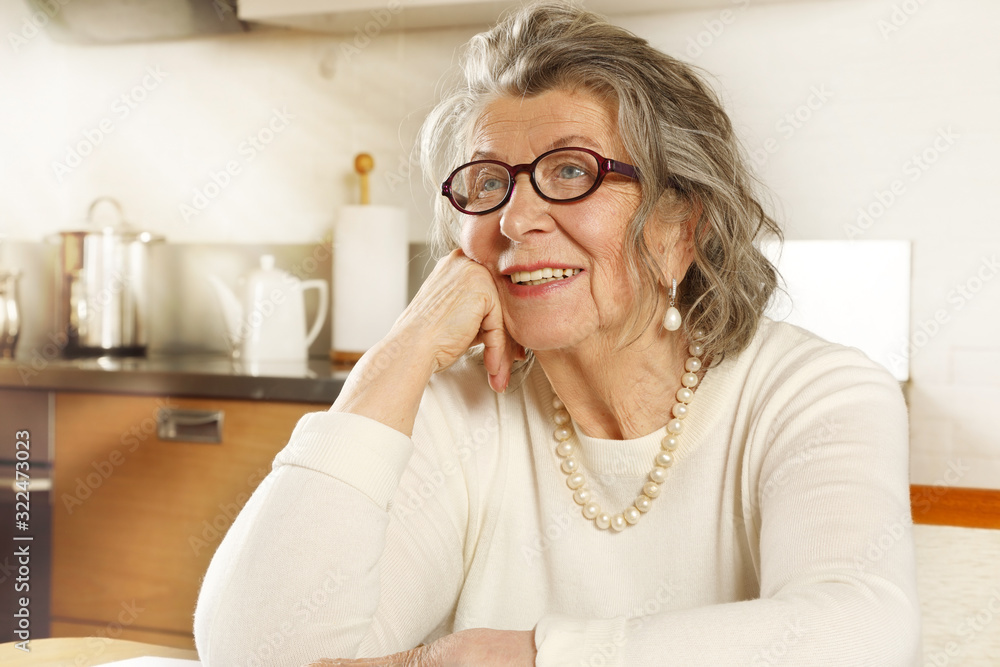 Portrait of a happy old woman sitting at the kitchen table Portrait of a happy old woman sitting at the kitchen table