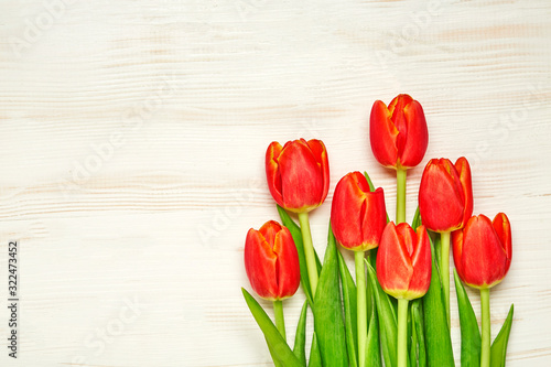 Red spring tulips on wooden table. Top view with copy space. Close up.