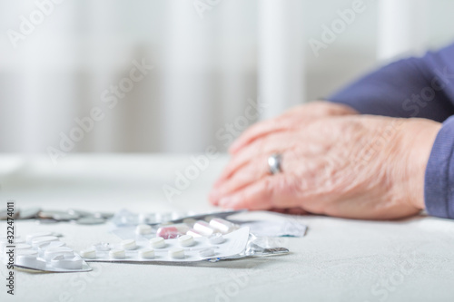 Closeup senior woman hands with pills and coins on table at home. An elderly pensioner counts money.