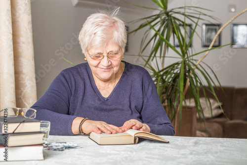 Senior woman reads concentrated in a book in the library in the retirement home