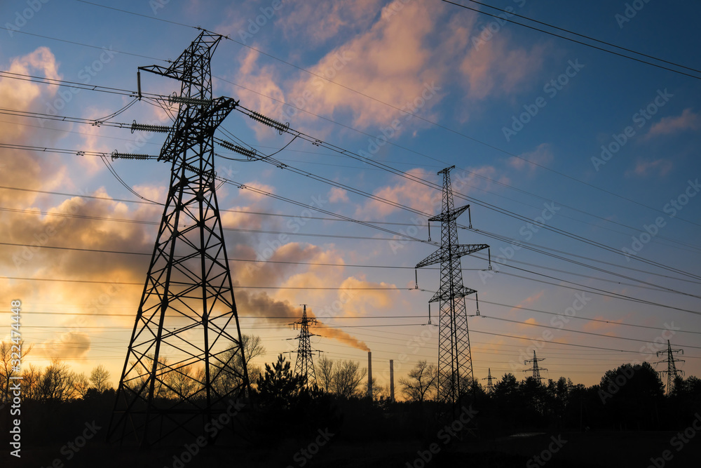 Fototapeta premium High-voltage power lines during fiery sunrise