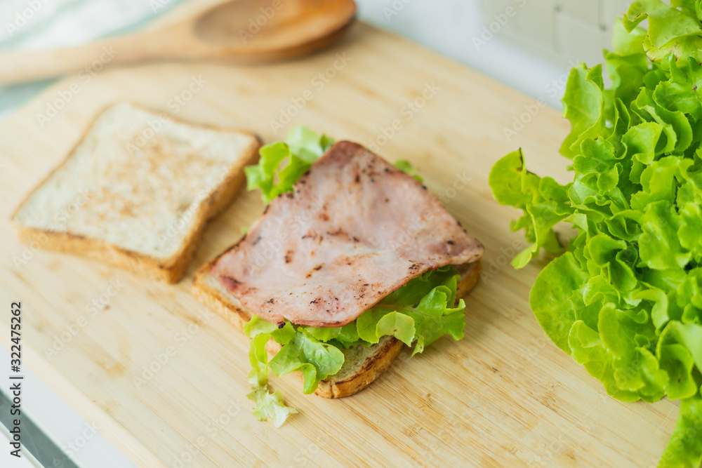 Tasty and fresh sandwiches in kitchen room. Man prepares lunch, serves grilled bread sandwich snack on top of wooden cutting board. Tasty and fresh sandwiches in kitchen room. Man prepares lunch, serves grilled bread sandwich snack on top of wooden cutting board.