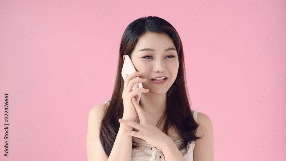 Happy cute girl laughing while talking on mobile phone. making friendly phone call, discussing good news, carefree communication. indoor studio shot isolated on pink background Happy cute girl laughing while talking on mobile phone. making friendly phone call, discussing good news, carefree communication. indoor studio shot isolated on pink background