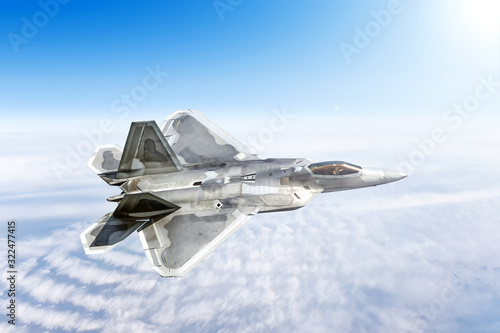 military airplane fighter jet aircraft flying high above cloudscape landscape against blue clouds sky background. Aerial top down view of modern supersonic plane