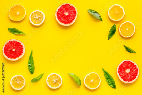 Fototapeta Naklejka Na Ścianę i Meble -  Citrus fruits - lemons, grapefruit slices - on yellow background mockup, frame top-down copy space