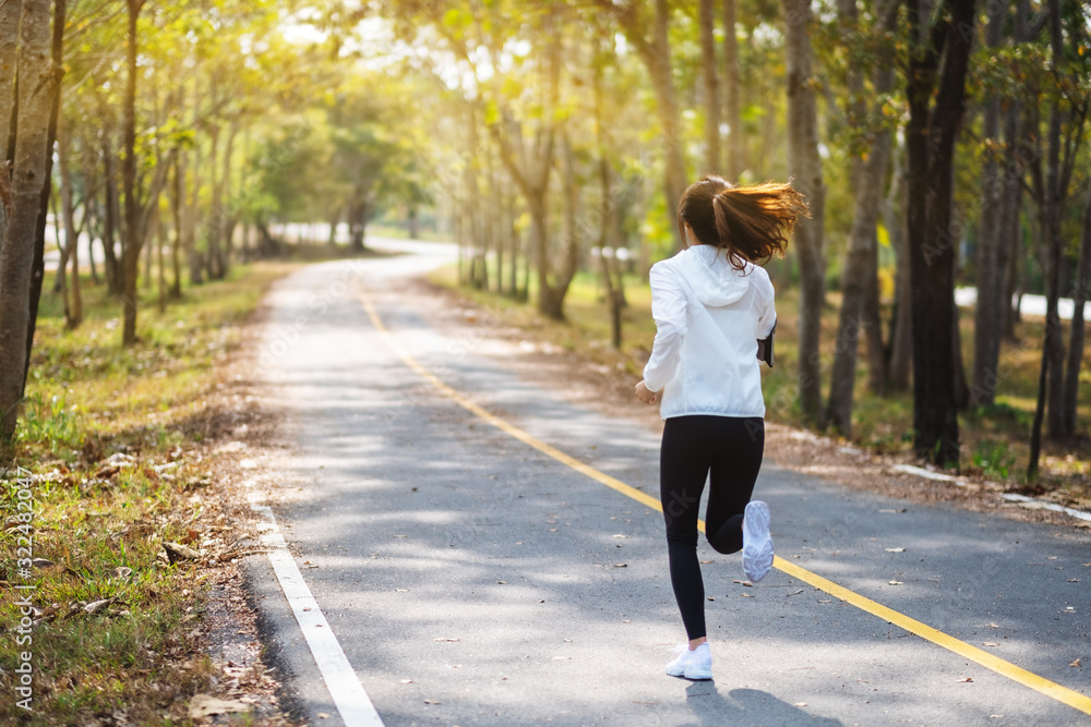 Rear view image of a young asian woman jogging in city park in the morning Rear view image of a young asian woman jogging in city park in the morning