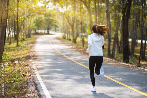 Rear view image of a young asian woman jogging in city park in the morning