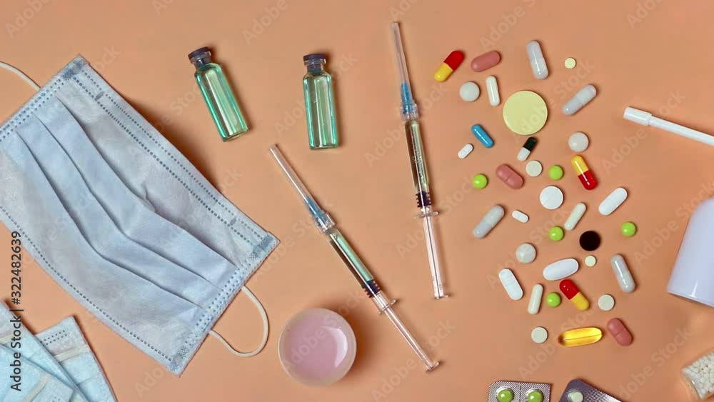 Medical preparation-face masks, medical gloves, ampoules and syringes with vaccine, pills, spray, homoeopathic remedies on peach background. Concept of protection, prevention and treatment of viruses Medical preparation-face masks, medical gloves, ampoules and syringes with vaccine, pills, spray, homoeopathic remedies on peach background. Concept of protection, prevention and treatment of viruses