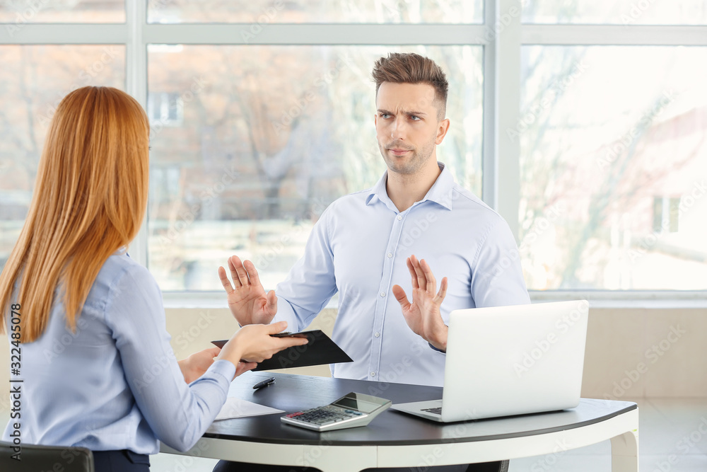 Bank manager working with displeased man in office Bank manager working with displeased man in office