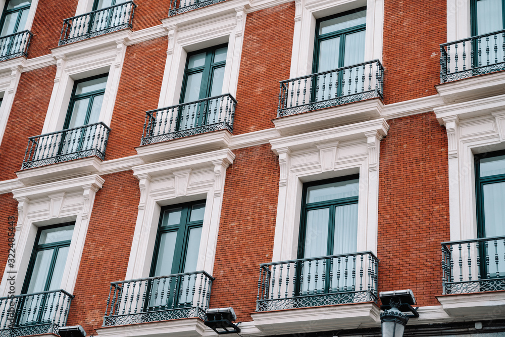 Obraz premium Beautiful building with red facade and balconies in Madrid Spain