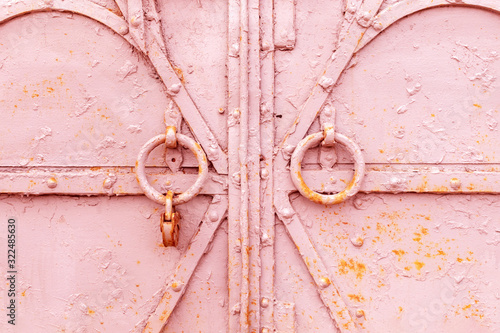 Obraz na plátně Closeup fragment of a closed old metal door or gate with round knockers and a rusty padlock
