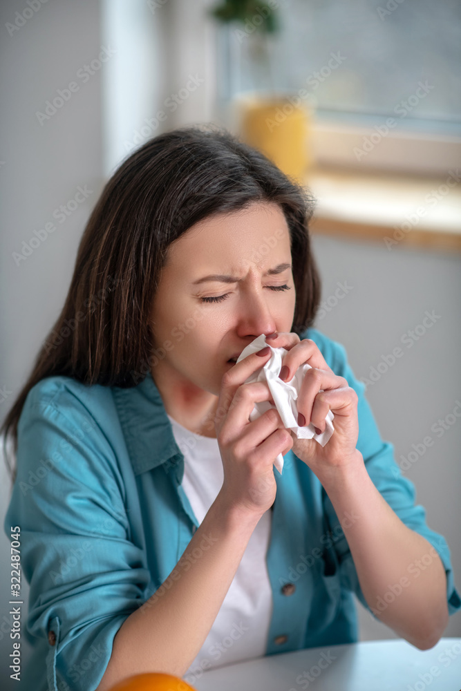 Young woman sneezing and using a napkin Young woman sneezing and using a napkin