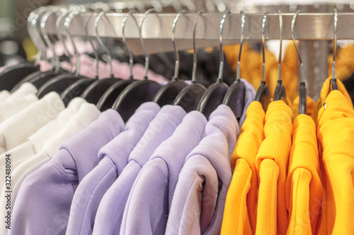 Multicolored sweatshirts hang on a hanger in store close-up.