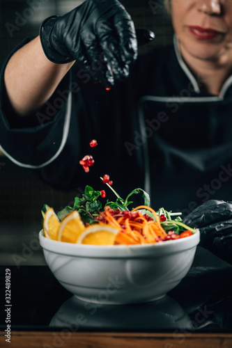 Chef in Restaurant  Decorating Salad with Pomegranate Seeds