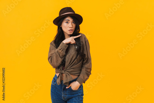 Image of young asian woman wearing hat smiling and pointing finger