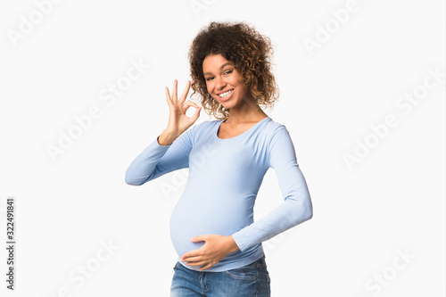 Valokuva Successful pregnancy. Happy afro woman gesturing okay