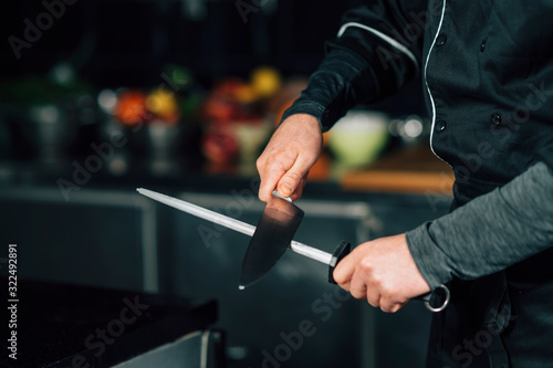 Male Chef Sharpening the Knife in the Kitchen photo