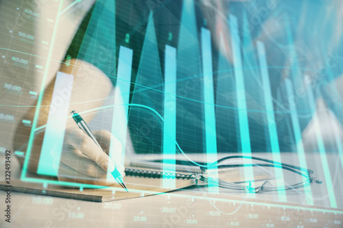 Multi exposure of woman's hands making notes with forex graph hologram. Concept of technical analysis.