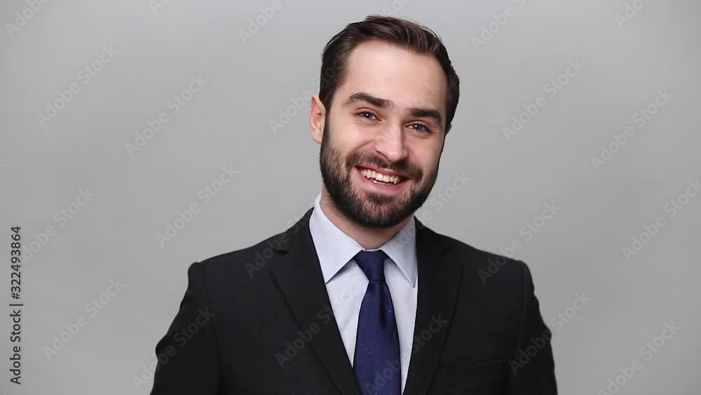 Handsome successful young business man in classic black suit shirt tie posing isolated on grey background studio. Achievement career wealth business concept. Mock up copy space. Smile looking camera Handsome successful young business man in classic black suit shirt tie posing isolated on grey background studio. Achievement career wealth business concept. Mock up copy space. Smile looking camera