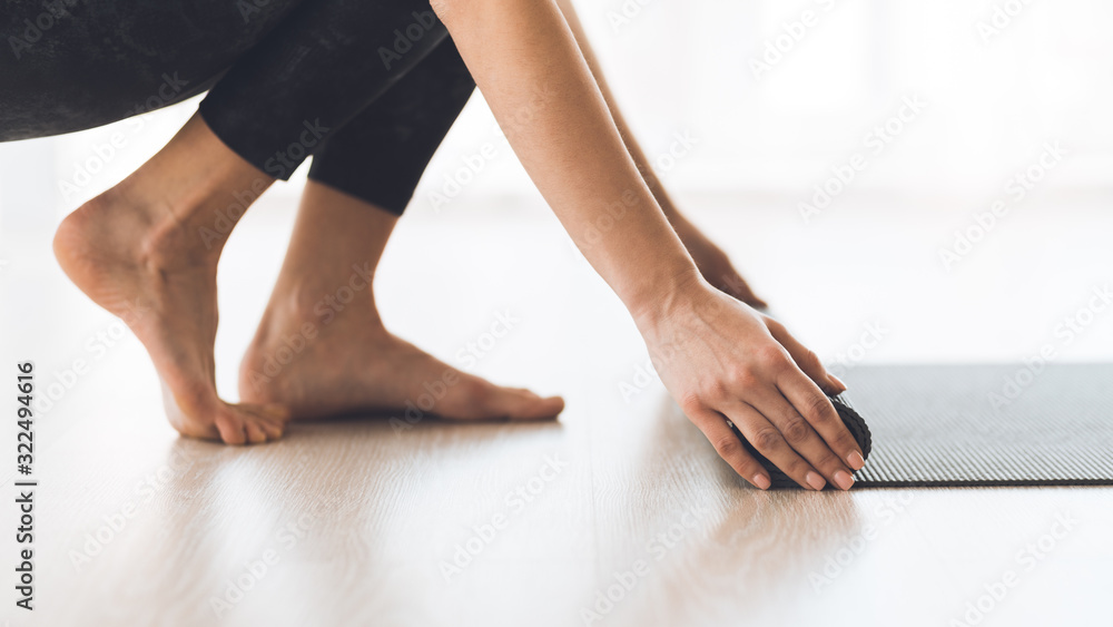 Woman rolling exercise yoga mat on wood floor at studio Woman rolling exercise yoga mat on wood floor at studio