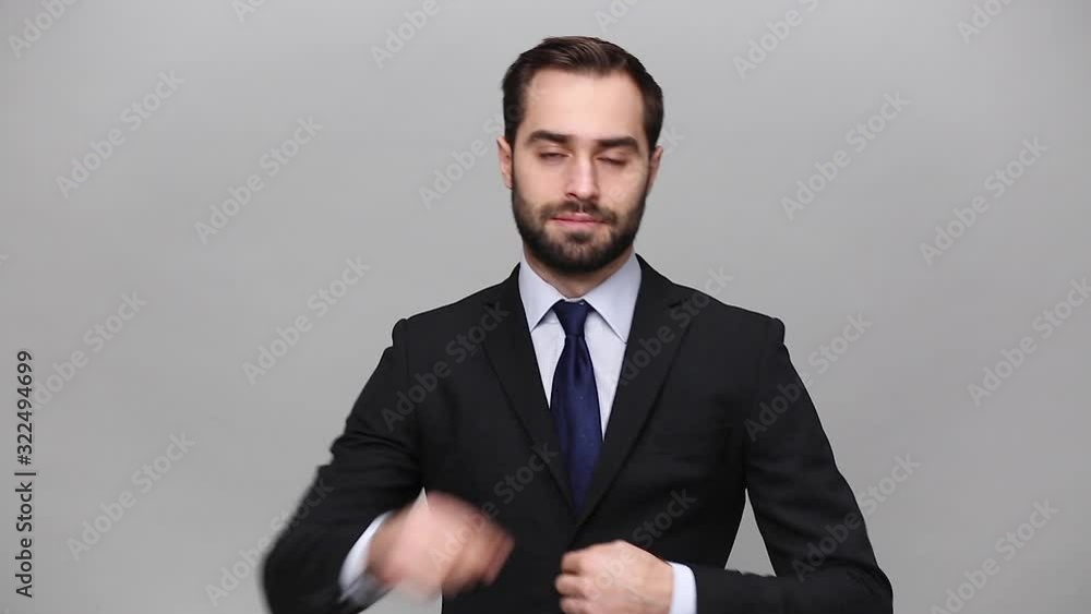 Successful bearded young business man in classic black suit shirt tie posing isolated on grey background studio. Achievement career wealth business concept. Mock up copy space. Suit up, looking camera Successful bearded young business man in classic black suit shirt tie posing isolated on grey background studio. Achievement career wealth business concept. Mock up copy space. Suit up, looking camera