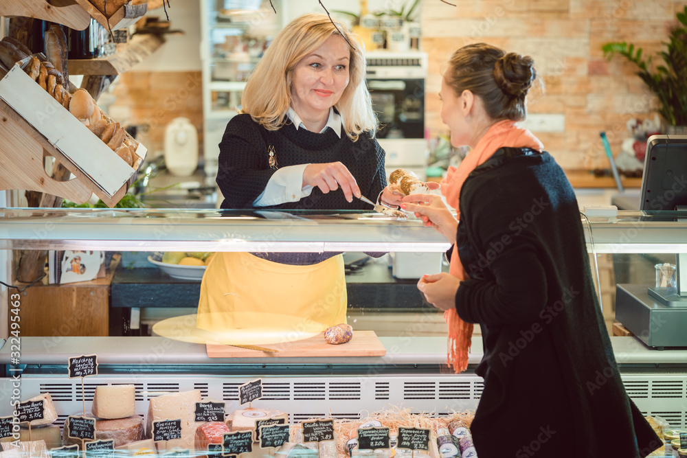 Customer and shop clerk at the cheese counter of supermarket Customer and shop clerk at the cheese counter of supermarket