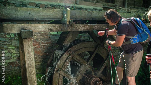 Couple is looking at and touching a old water mill. Sunny day with flare. Prevalje, Slovenia photo