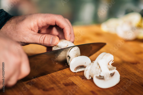 Cooking dinner - Chef Holding a Knife, Cutting Mushrooms on a Wooden Cutting Board
