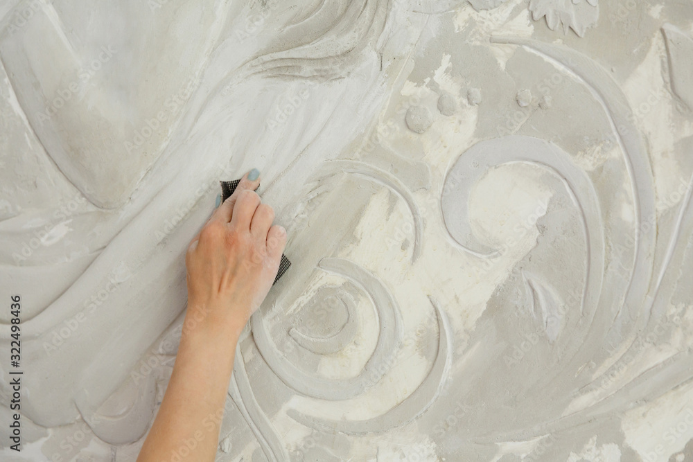 woman at work, sandpaper handles the bas-relief on the wall woman at work, sandpaper handles the bas-relief on the wall