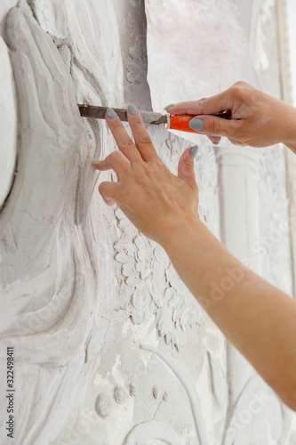 female hands at work, a chisel carves a bas-relief pattern