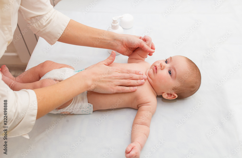 Masseuse massaging little baby, squeezes cream. hypertonicity correction Masseuse massaging little baby, squeezes cream. hypertonicity correction