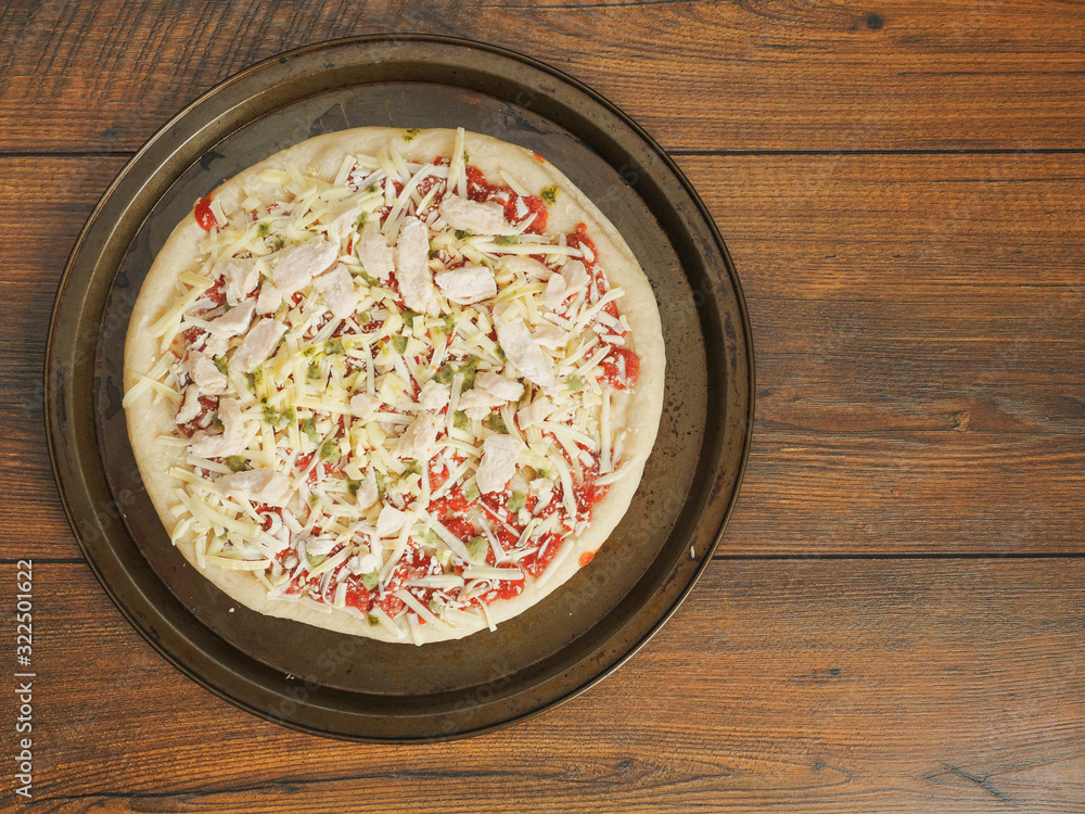 Fresh uncooked chicken pizza on a metal trey ready for cooking, Italian style dish with cheese and tomato sous. Top view. Fresh uncooked chicken pizza on a metal trey ready for cooking, Italian style dish with cheese and tomato sous. Top view.