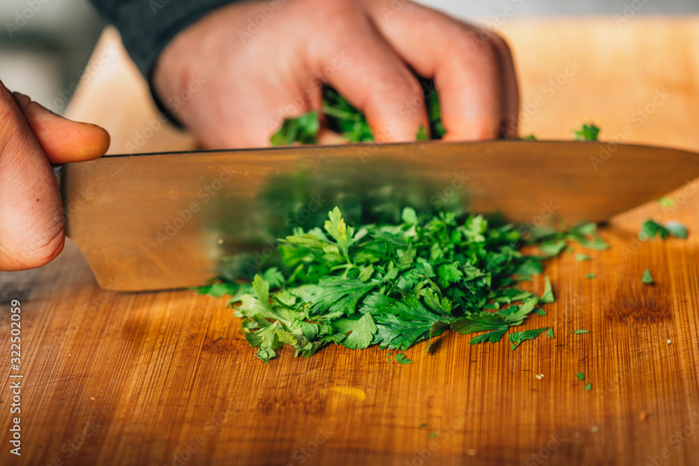 Chef Holding a Knife and Cutting Parsley on a Wooden Cutting Board Chef Holding a Knife and Cutting Parsley on a Wooden Cutting Board
