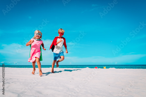 happy boy and girl play superheros on beach vacation