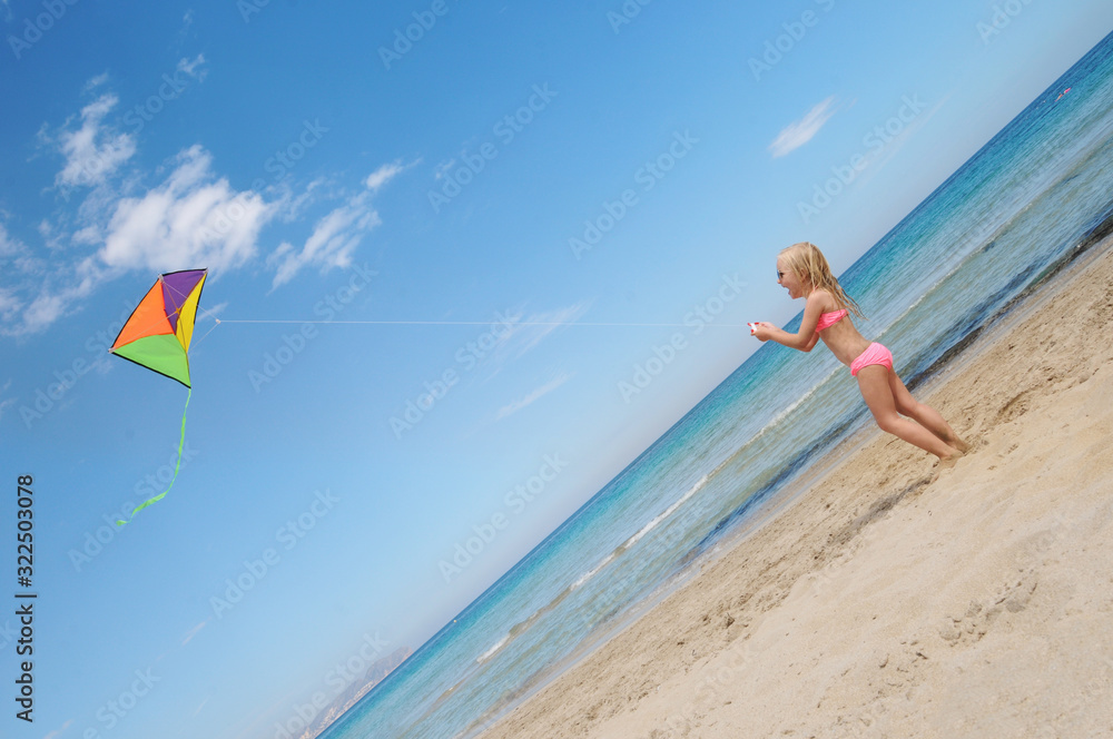 Little happy girl playing with flying kite. Summer vacation concept